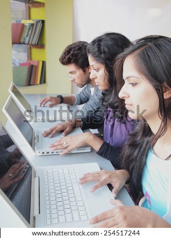 Group of students doing on-line training over laptop computers in the library.