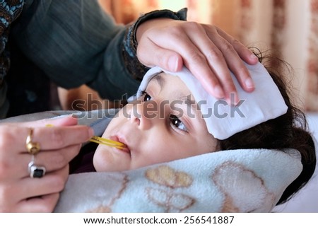 Mother measuring fever of her sick child.