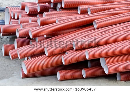 Industrial background - red plastic corrugated pipes for sewage close-up