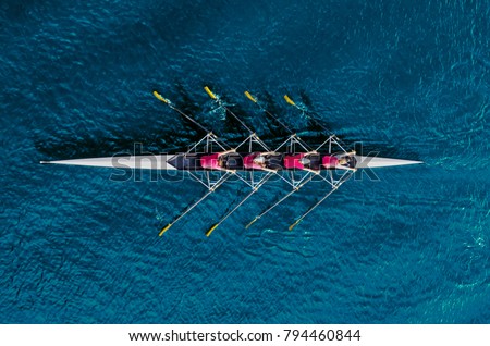 Women\'s rowing team on blue water, top view