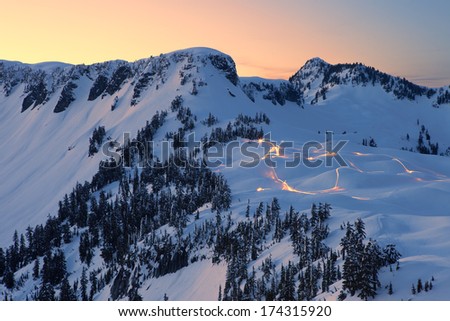 Lights of Snowmobiles on Snow Mountain at Sunset