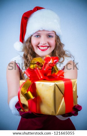 Beautiful woman in a red dress and hat of Santa with a big gift box.