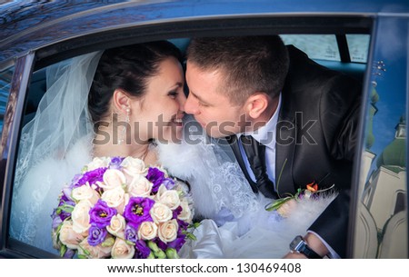 Closeup of newlywed couple kissing in wedding car