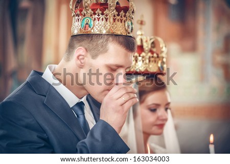 priest gives wine to a crowned groom  during orthodox wedding ceremony