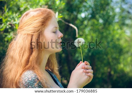 portrait of the rural red-haired girl with a dandelion