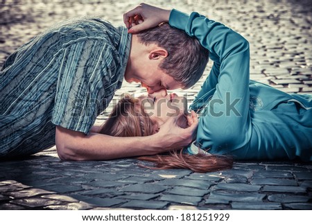 Couple of teenagers lying in street together