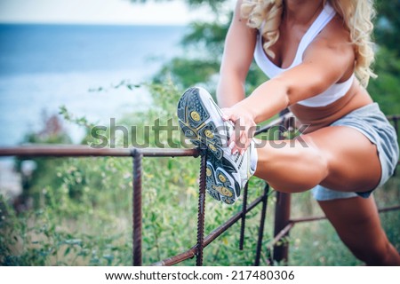 Young fitness woman stretching muscles before sport activity - outdoor in park