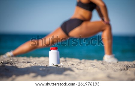 bottle of sports food on sand against the training girl