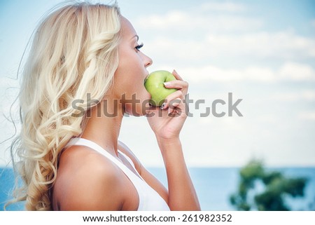 Young woman with an apple against sky background