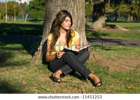 The student with the book near a tree in park