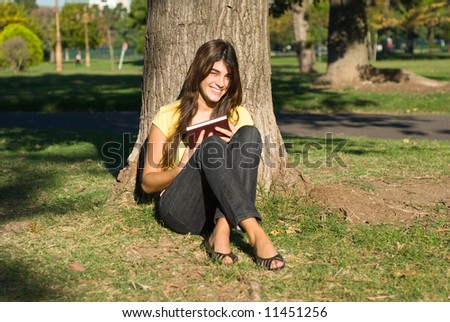 The student with the book near a tree in park