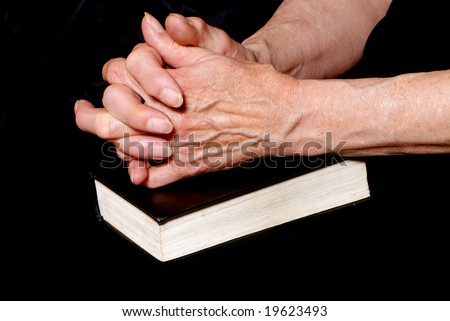 Hands of old woman closed in a prayer on bible