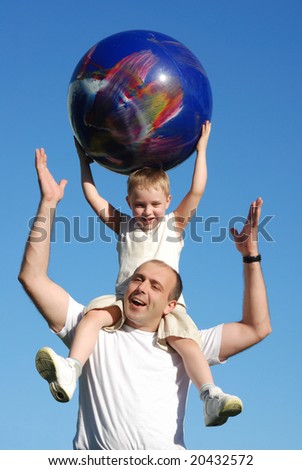 The son on shoulders at the father against the sky
