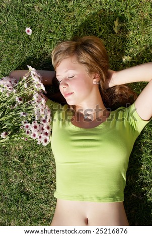 The young girl with a bunch of flowers laying on a grass
