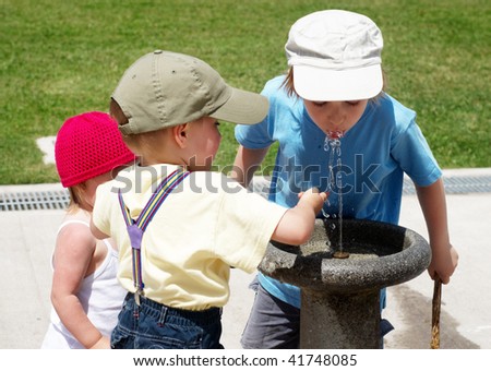 Children drinking water in a drinking fountain in park