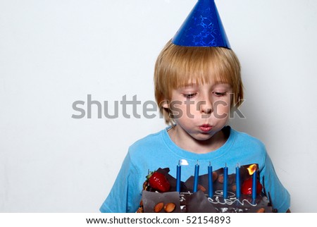 boy blowing on the candles placed in the cake