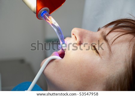 dentist curing the patient\'s teeth with ultraviolet lamp