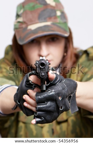 The woman soldier with a pistol in hands on a light background