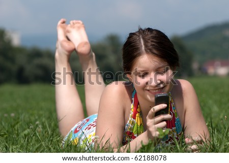 Girl speaks by mobile phone against summer green nature