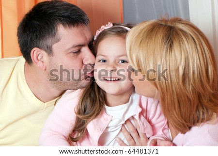 parents kissing daughter portrait looking very happy