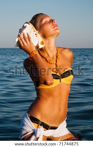 portrait of a young gorgeous female listening seashell song