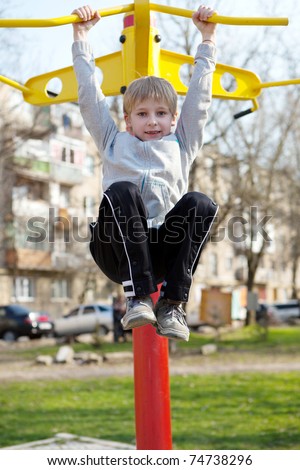 The small child hanging on a horizontal bar