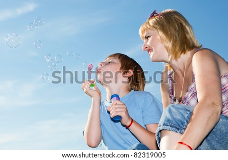 Boy and mother with soap bubbles against a sky