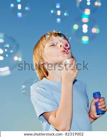 Boy with soap bubbles against a sky