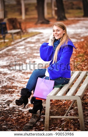 The happy young girl sitting on a bench in park