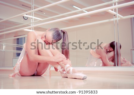Beautiful ballerina sitting on floor in dance studio