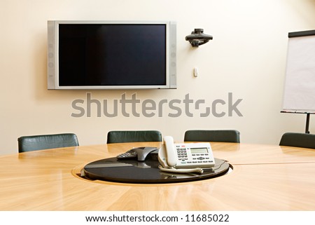 Hall of meetings with a round table, the screen on a wall, phones and black chairs