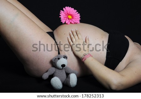 Closeup of belly pregnant with teddy bear and flower