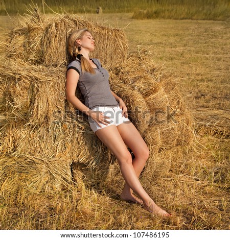 Beautiful woman on field near a haystack outdoors