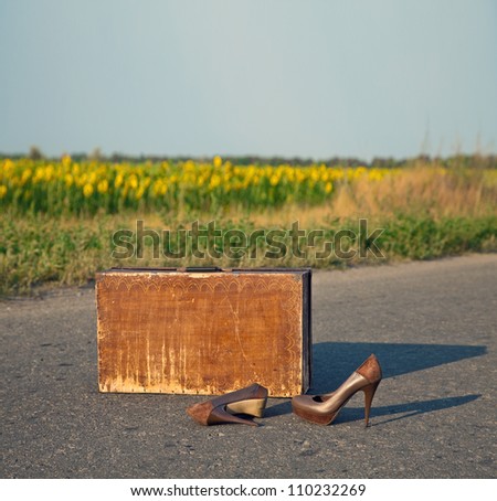 Old suitcase with brown shoes left on dirt road