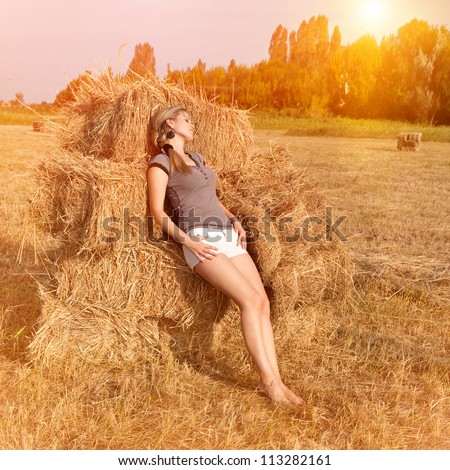 Beautiful woman on field near a haystack outdoors