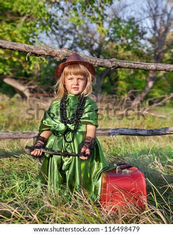 small girl with a suitcase in green dress, outdoors