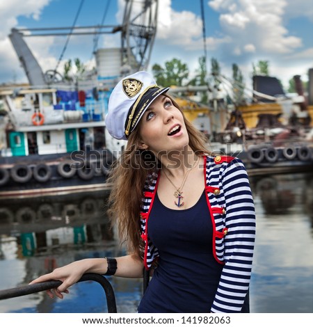 Fashion portrait of beautiful  girl - captain with binocular and cap in port, at the river view