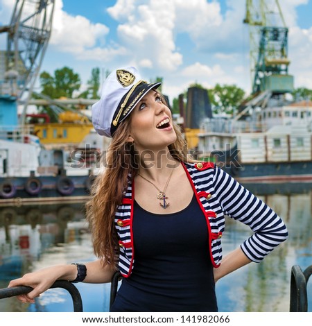 Fashion portrait of beautiful  girl - captain with binocular and cap in port, at the river view
