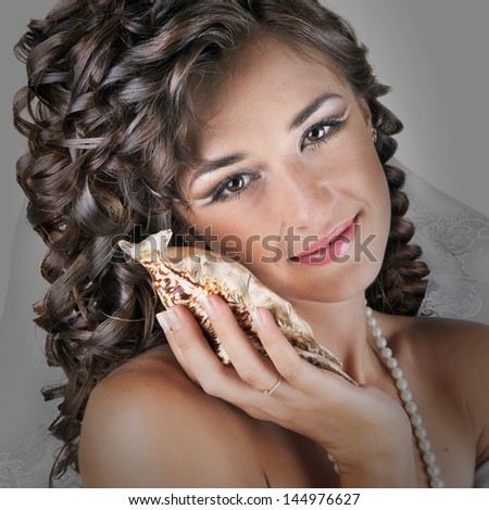 Young beautiful bride woman in wedding dress and luxury coiffure with cockleshell