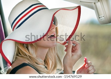 Pretty girl in a car. Cute blond woman makes up lips in the car