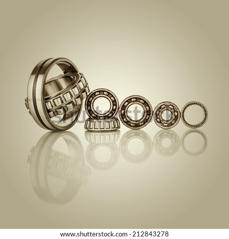 Collection of different steel chromed shiny ball roller bearings on  retro vintage background with reflection effect, closeup