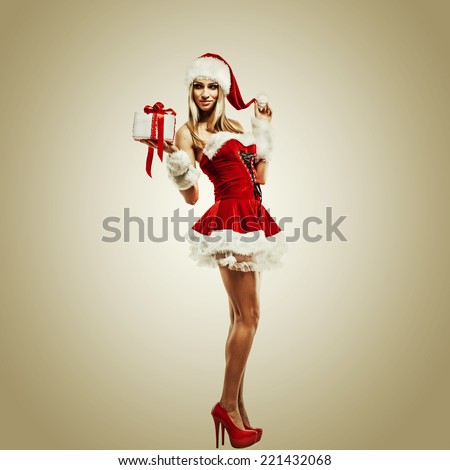 Beautiful woman in Santa Clause costume with Christmas gift. Winter portrait of sexy girl with copy space. Attractive new year and xmas party lady