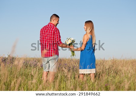 Love story. Beautiful young couple walking in meadow, outdoor. Portrait of stylish fashion man and woman posing in summer in field. Series. Back view