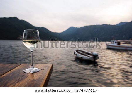 A glass of white wine at sunset next to the sea