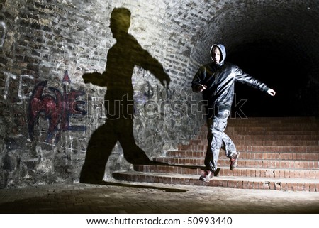 Man running trough dungeon, jumping with shadow on the wall