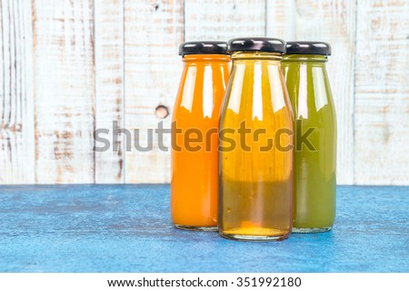 orange kiwi and apple  Juice bottle on a wooden background.