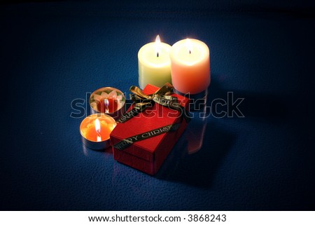 Burning candle with christmas gift box in the night