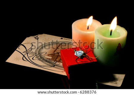 couple candle, gift box and christmas invitation on the dark background