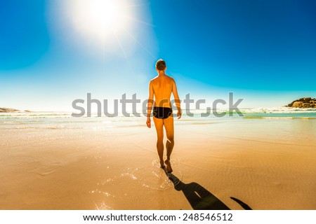 young man walking at the beach ocean shore relaxing and having a moment for himself, in south africa