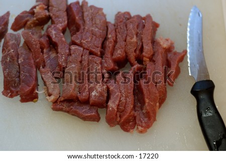 Raw Meat slices on a cutting board with a knife